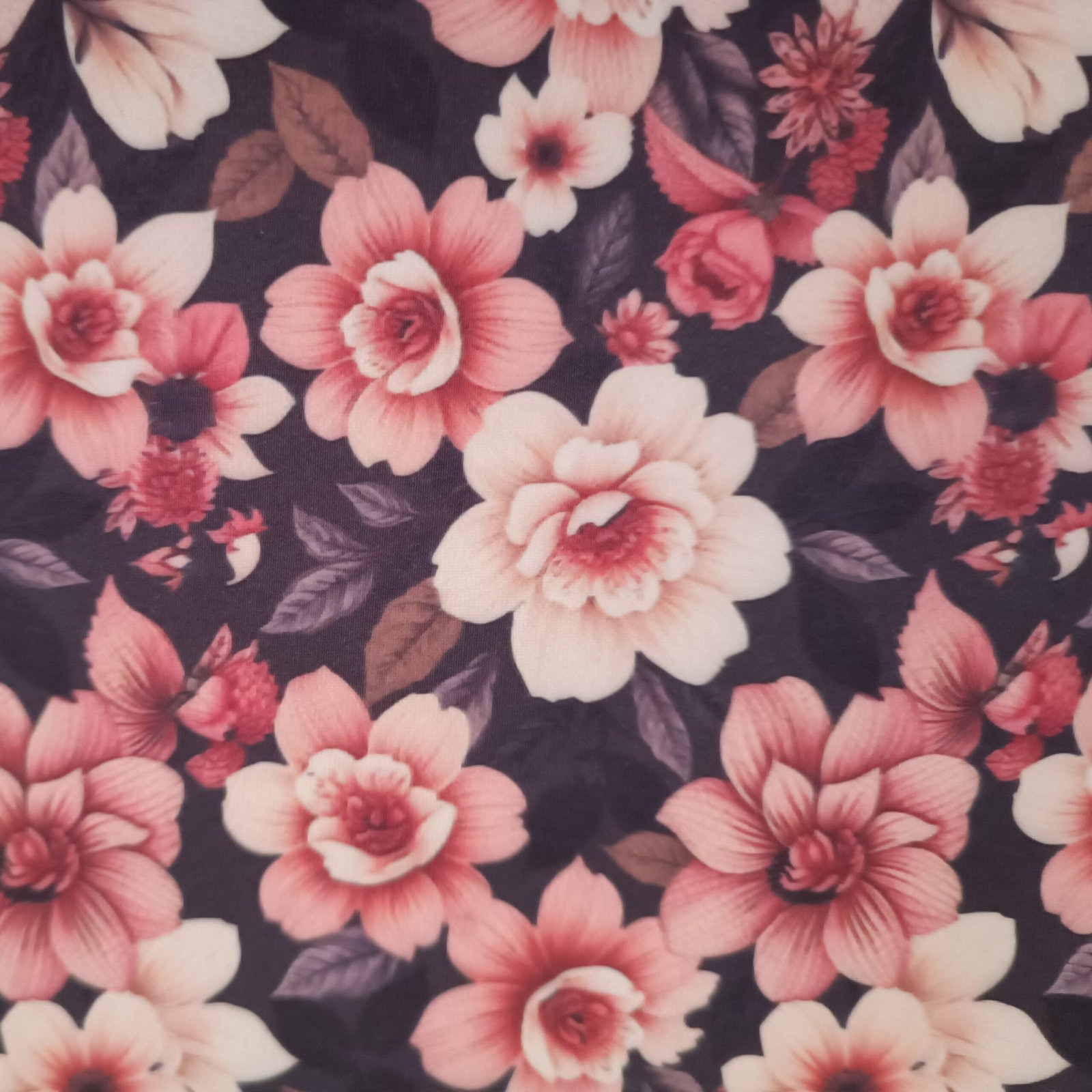 Tecido Microfibra Estampa Digital floral com flores em tons de rosa e folhagens escuras sobre fundo preto, da Evelin Tecidos e Aviamentos.