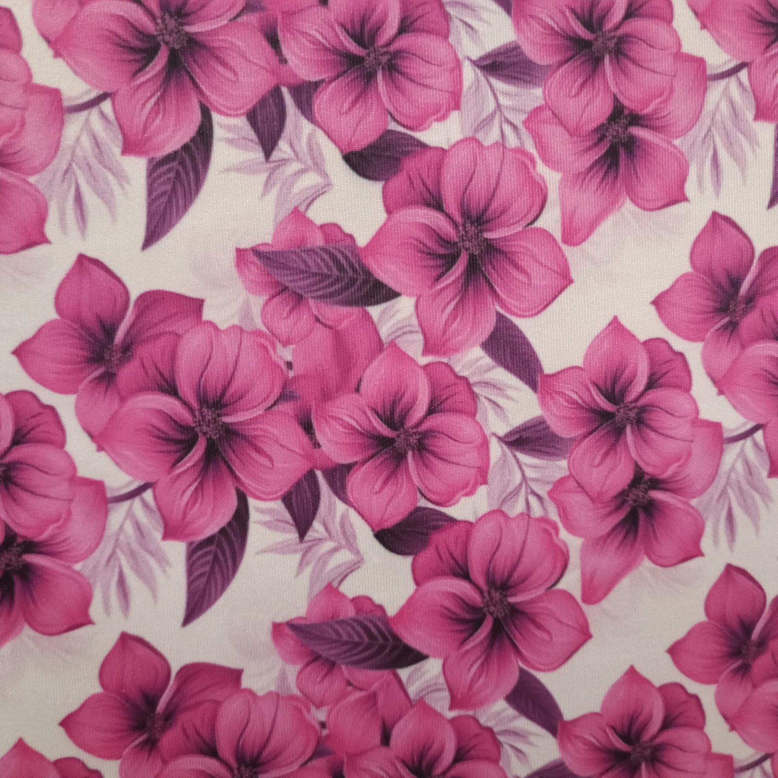 Tecido Microfibra Estampa Digital floral com flores magenta vibrantes e folhagens roxas sobre fundo branco, da Evelin Tecidos e Aviamentos.