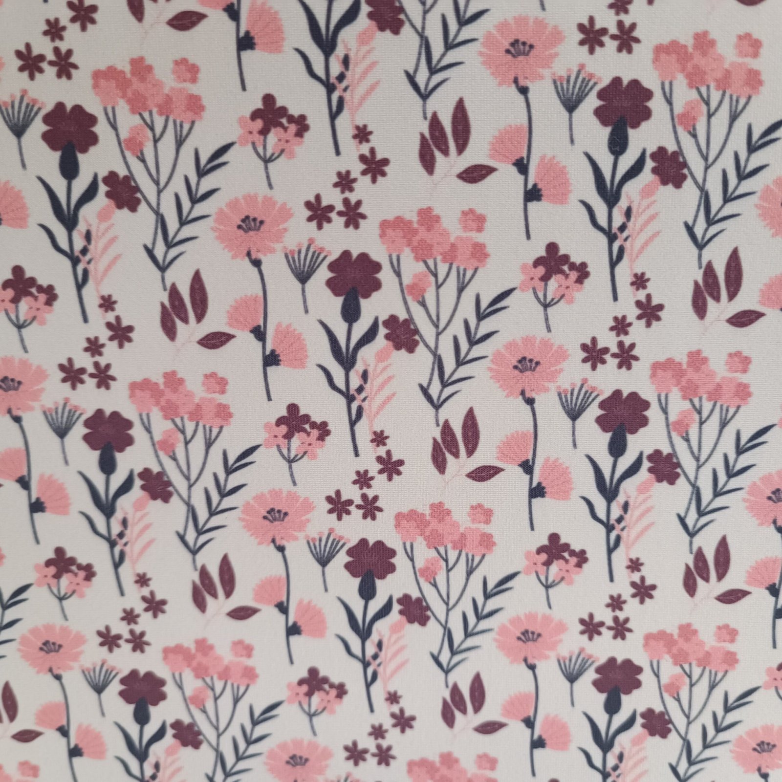 Tecido Microfibra Estampa Digital floral miúdo com flores rosa, folhagens escuras e pontinhos sobre fundo branco, da Evelin Tecidos e Aviamentos.