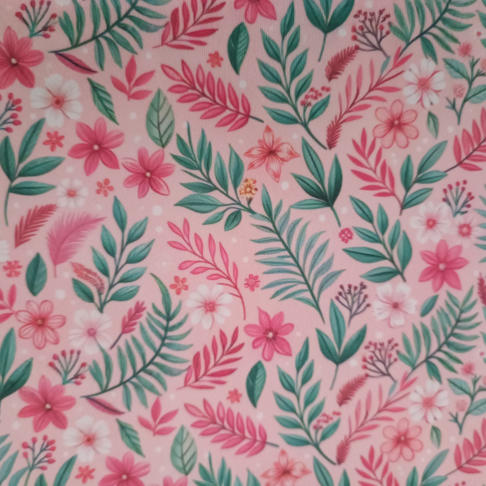 Tecido Microfibra Estampa Digital tropical com folhagens verdes e rosas, flores pink e brancas sobre fundo rosa claro, da Evelin Tecidos e Aviamentos.