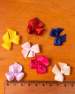 Imagem de um laço gordinho feito de fita de cetim, no tamanho número 02, em uma cor viva ou neutra, destacando sua forma arredondada e acabamento brilhante, ideal para detalhes em lingerie.