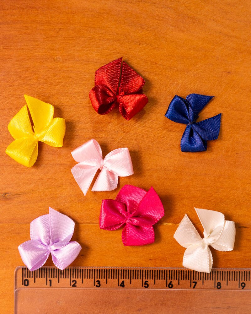 Imagem de um laço gordinho feito de fita de cetim, no tamanho número 02, em uma cor viva ou neutra, destacando sua forma arredondada e acabamento brilhante, ideal para detalhes em lingerie.