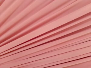 Suede sintético flexível em tom pastel de goiaba, perfeito para acabamentos e peças sofisticadas de moda íntima, disponível na Evelin Tecidos.