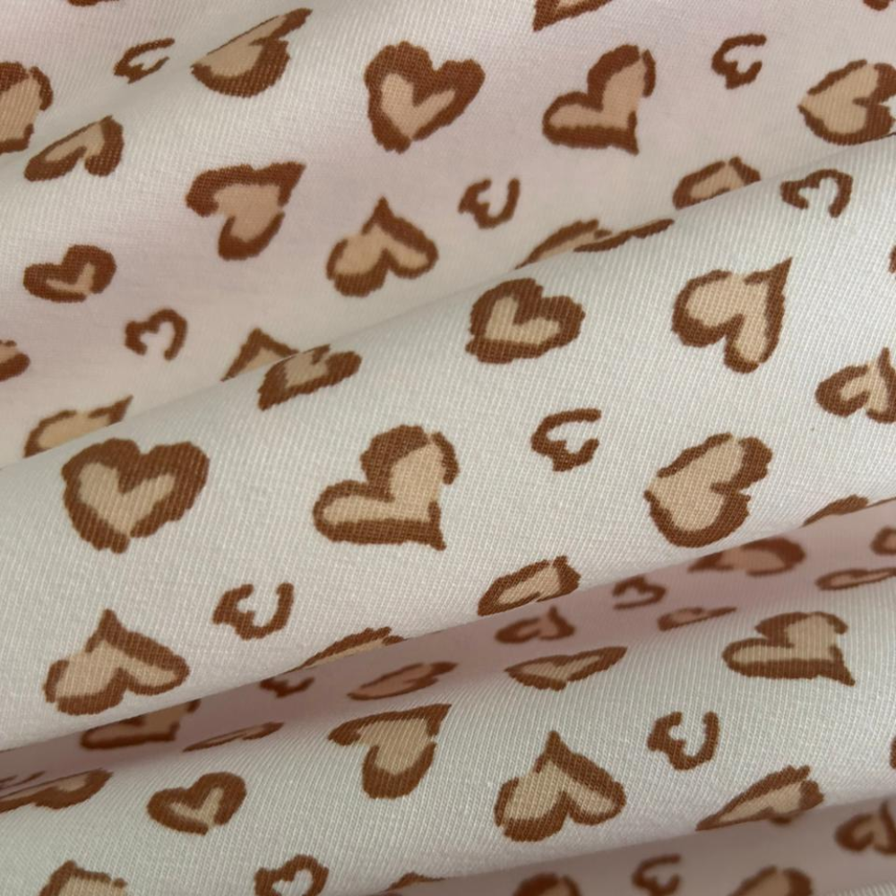 Tecido Cotton Estampado Coração Caramelo Off. Estampa de corações bicolores em caramelo e nude sobre fundo off-white, 96% Algodão, para pijamas e moda íntima.